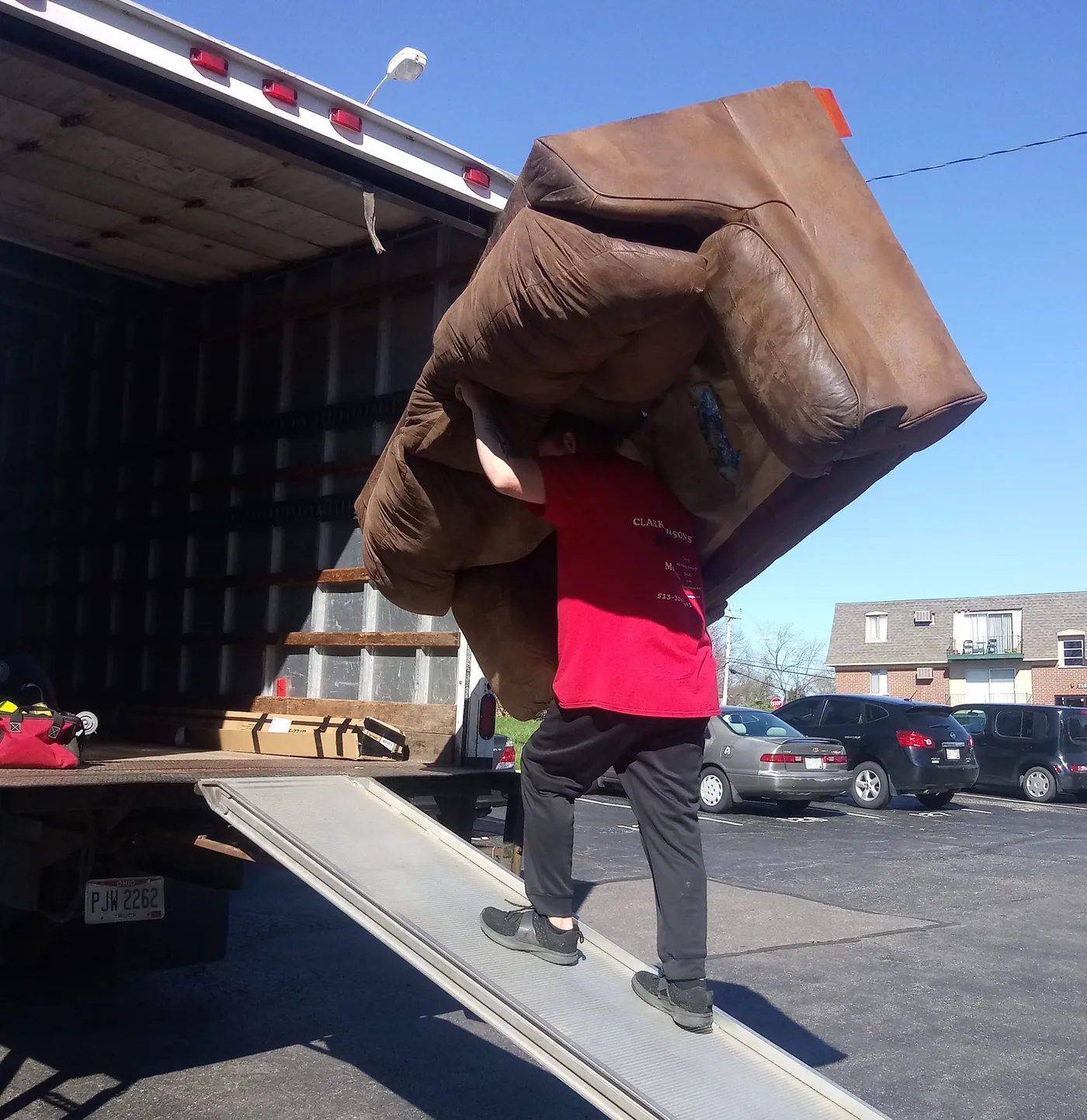 Mover carrying a leather sofa over his head up the truck ramp
