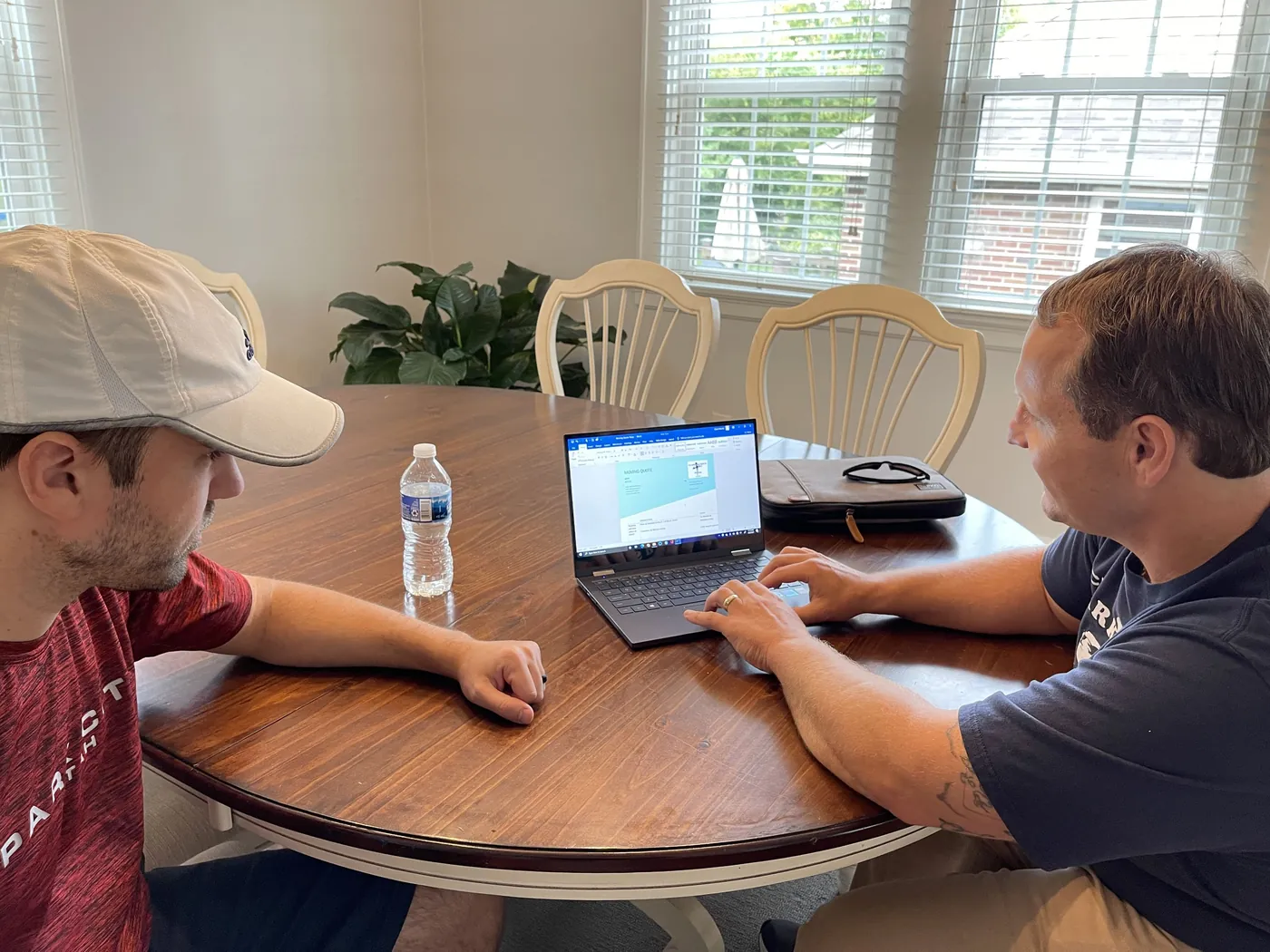Clark and Sons estimator going over a move on a laptop with a homeowner at a kitchen table