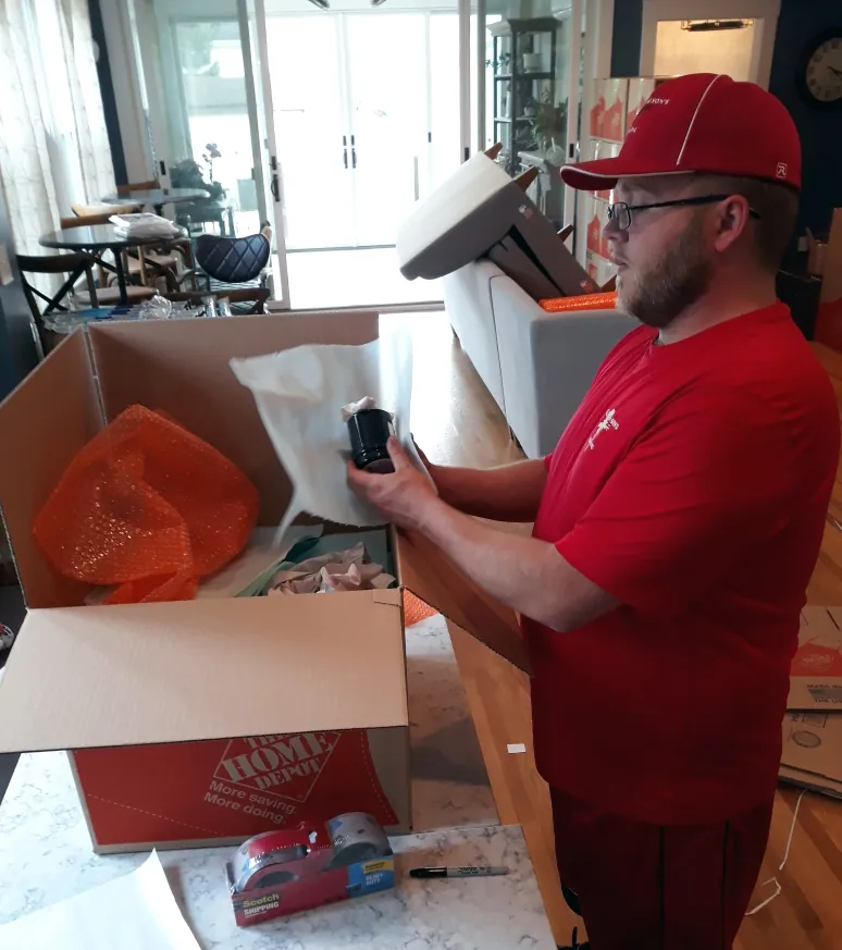 Mover wrapping kitchenware into a moving box