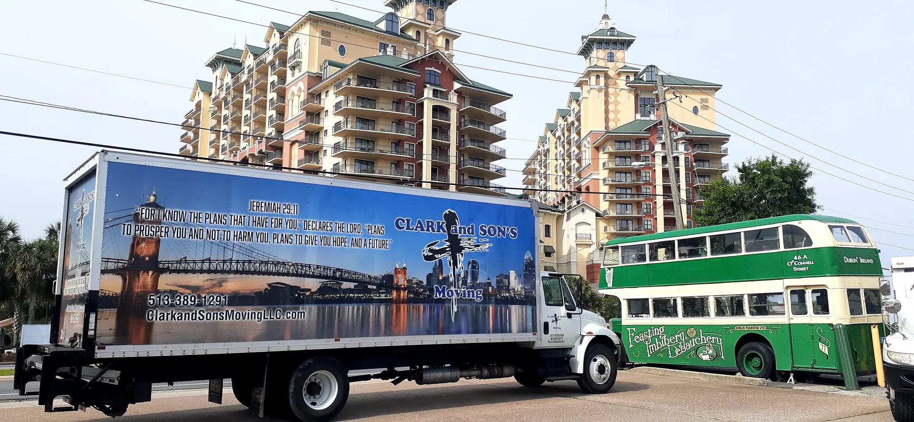 A Clark and Sons truck wrapped with the Cincinnati skyline parked below high-rise apartments